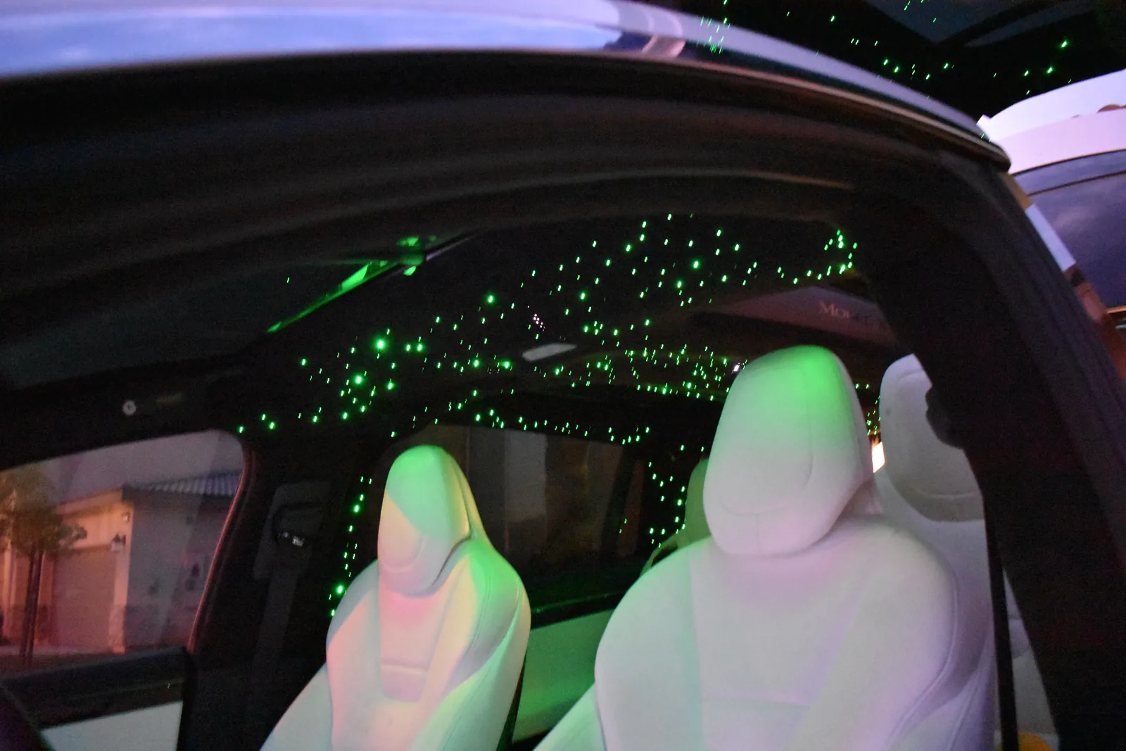 Tesla Model X white seats beneath a green-lit starlight headliner around the glass roof